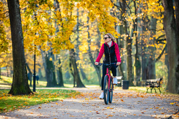 Urban biking - middle-aged woman riding bike in city park
