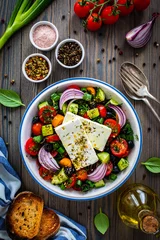 Gordijnen Fresh Greek salad - feta cheese, cherry tomatoes, cucumber, black olives and onion on wooden table  © Jacek Chabraszewski