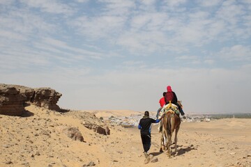 Tourist riding on a camel in the sandy desert of Aswan in Egypt