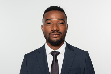 smiling african american businessman in suit with tie isolated on grey