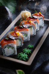 Two types of traditional Japanese rolls. Rolls with smoked salmon and rolls with smoked eel. Creamy cream and cucumber inside the rolls.Dark background. Close-up.Out of focus.