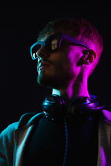 Neon portrait of a bearded man wearing headphones on the neck, wearing parka and mate sunglasses. Hacker portrait © diignat