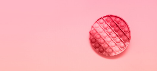 Colorful anti-stress fidget push pop it sensory toys on pink background.