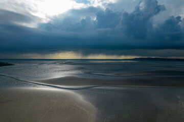 Landscape of a beach surrounded by the sea under a cloudy sky on a stormy day