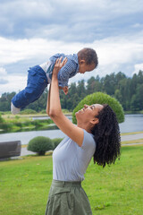 Young beautiful dark-skinned mother holds her baby up