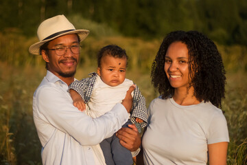 A young mixed dark-skinned family with a child outdoors