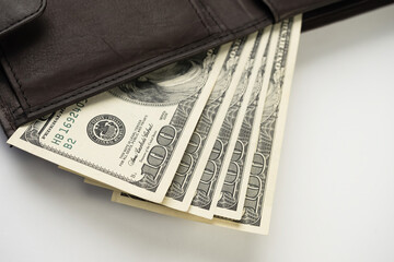 Leather wallet full of money on white background - fan of one hundred US banknotes with president Franklin portrait. Cash of hundred dollar bills, paper currency.