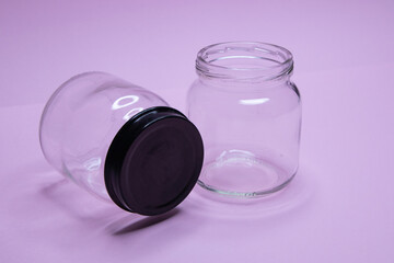 Small glass jar with metal lid on purple background
