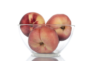 Three juicy organic peaches in a glass bowl, close-up, isolated on white.
