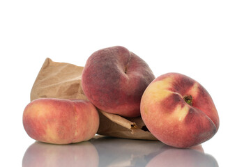 Three juicy organic peaches with a package of paper, close-up, isolated on white.