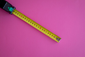 Top view of a yellow measuring tool on a pink background