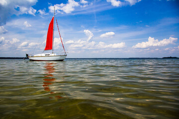 Small yacht with a red sail.
