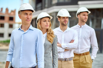 Four adult people in hardhats standing on the building site