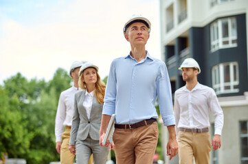 Four colleagues in hardhats inspecting the construction site
