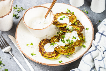 Zucchini pancakes with spinach, hepbs and parmesan cheese, served with sour cream or yogurt. Plant-based eating, alt-meats cutlet.