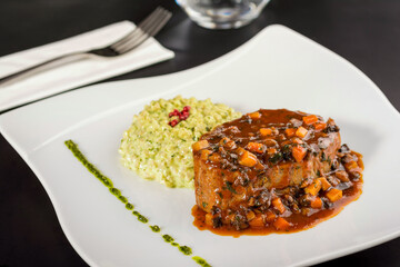 Beef tenderloin and basil risotto on a porcelain plate