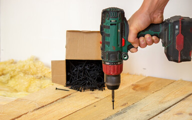 the man twists the screws into the board. Repair of the floor in the house. Selective focus.