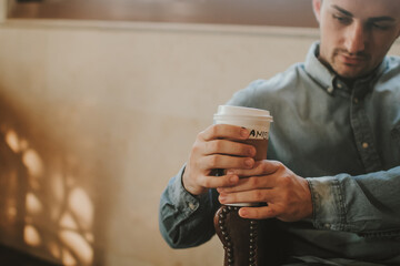 Young Adult Person Hold a Take-Away Paper Cup of Coffee in Hands and Drink Coffee in Cafe