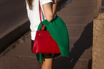 woman walking with pullover hanging on her handbag, sunny day shot