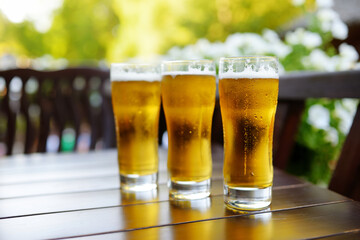 Three glasses of cold beer on a table in an outdoor restaurant.