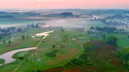 Incredibly beautiful and scenic red sunrise over fog shrouded rural landscape with golf course and neighborhood.