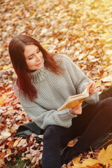 Portrait of pretty young woman in casual clothing in autumn, reading book