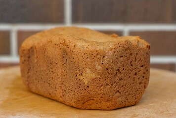 Loaf of homemade freshly baked bread on brown brick wall background