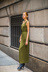 Woman Relaxing on Street. Dressing in a green, long Maxi Tank Dress,  black dress sandals, a young black girl is standing by old fashion style window and wall, waiting for you..