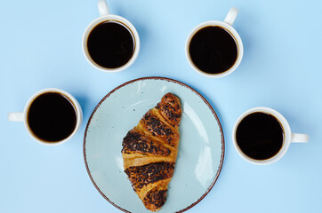 Businessman working morning with cups of hot black coffee and sweet croissant on blue background. Top view, copy space, mockup. Flat lay. Healthy food concept. Modern breakfast food.