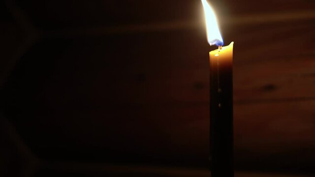 Religion, holidays, concept - Panning along rays of light from window in smoky dusty room falling on altar throne in Christian Orthodox temple with burning candle lamp nearby menorah under chandelier.