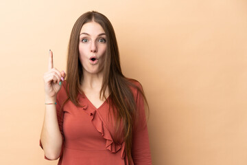 Obraz premium Young caucasian woman isolated on beige background intending to realizes the solution while lifting a finger up
