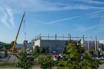 Obraz premium Cranes and lifts carrying concrete walls for installation on a warehouse and office construction site