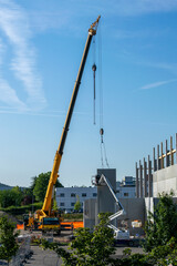 Cranes and lifts carrying concrete walls for installation on a warehouse and office construction site
