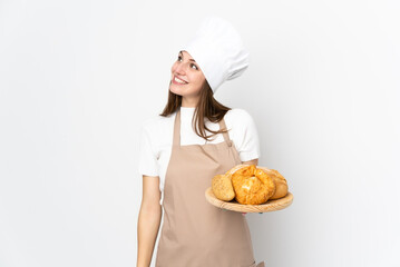 Young woman in chef uniform isolated on white background laughing and looking up