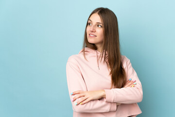 Obraz premium Young caucasian woman isolated on blue background looking to the side