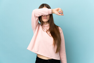Young caucasian woman isolated on blue background covering eyes by hands