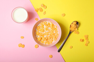 Crispy cornflakes with milk for breakfast on a colored background close-up.