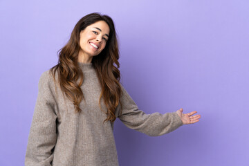 Woman over isolated purple background extending hands to the side for inviting to come