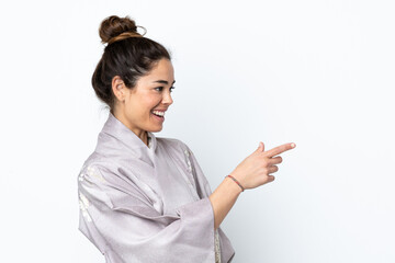 Woman wearing kimono over isolated background pointing finger to the side and presenting a product