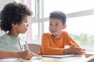 interracial boys talking during lesson in classroom