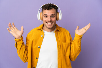 Young caucasian handsome man isolated on purple background surprised and listening music