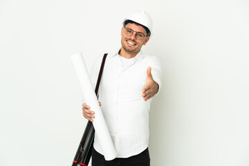 Young architect man with helmet and holding blueprints isolated on white background shaking hands for closing a good deal