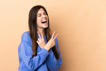 Teenager Brazilian girl over isolated background smiling and showing victory sign