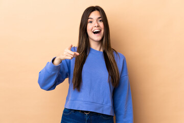 Teenager Brazilian girl over isolated background surprised and pointing front