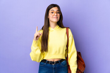 Teenager Brazilian student girl over isolated purple background pointing with the index finger a great idea