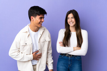 Young couple over isolated purple background smiling a lot