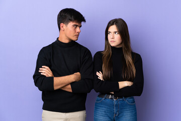 Young couple over isolated purple background annoyed angry in furious gesture