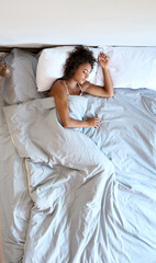 Peaceful young Afro American mixed race lady laying sleeping on modern orthopedic mattress bed in...