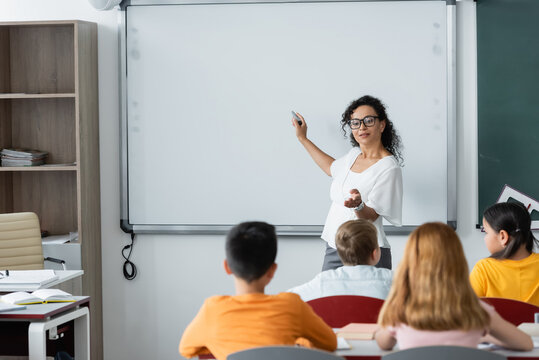 african american teacher pointing with hand while standing near whiteboard during lesson