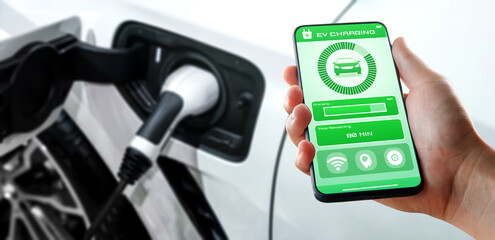 EV charging station for electric car with mobile app display charger status . The electric power is produced from sustainable resources to supply to charger station in order to reduce CO2 emission . - obrazy, fototapety, plakaty